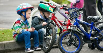 Kinder sitzen am Weltkindertag neben Ihren Fahrrädern rot und blau OnFaSu